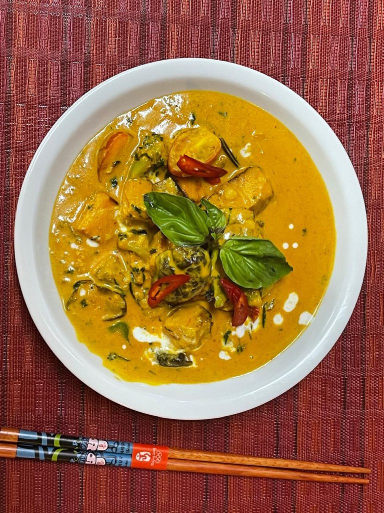 A bowl of Thai curry with basil and red chilli